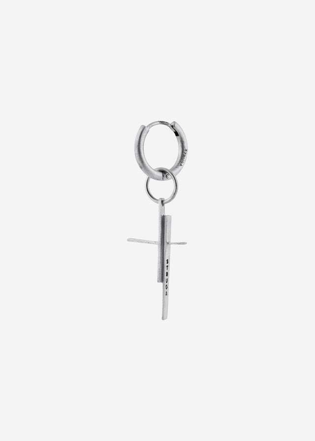 Hinged hoop earring in cool white metal with a doubled offset cross pendant, pale grey studio shot — STRUGA