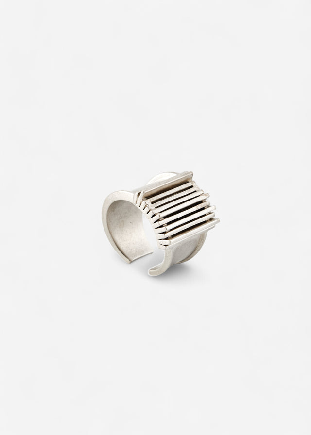 Open-band 925 silver ring, three-quarter view: raised grille of parallel bars on the face, matte pale-grey surface.
