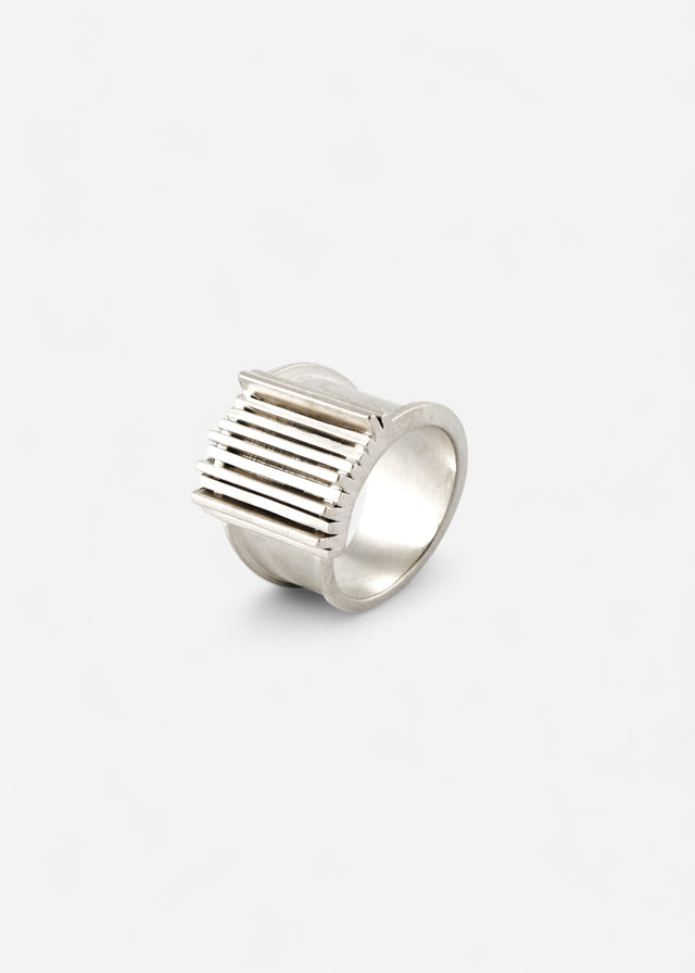 Wide heavy Brutalism V.1 silver ring, its face ribbed with parallel bars, on a light background — STRUGA