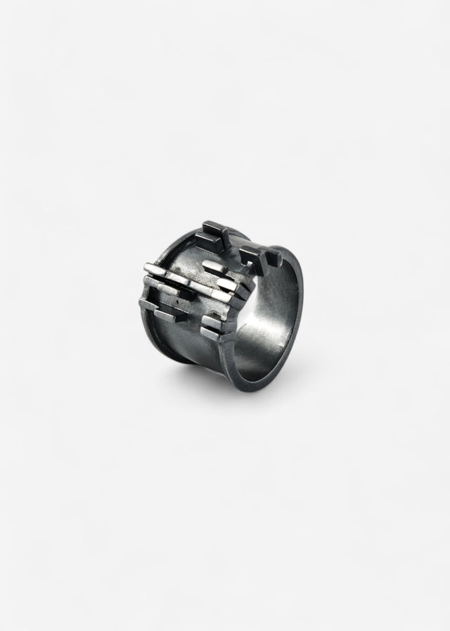 Wide oxidised 925 silver ring: dark recesses, bright edges, short bars stepping across the face.