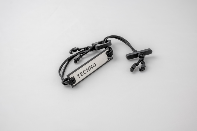 One Display Techno bracelet: mirrored plate engraved TECHNO in a black carbon frame, cord with a carbon toggle bar.